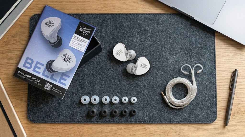 Auriculares Kiwi Ears Belle en acabado plata junto a su caja oficial, cable de 2 pines bañado en plata y 6 pares de almohadillas sobre tapete de fieltro